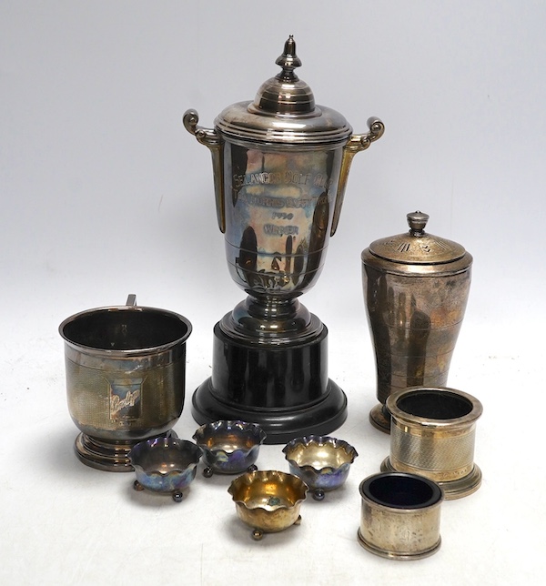 A George V silver trophy cup and cover, an Art Deco silver sugar shaker, a similar engine turned silver christening cup, and six silver salt cellars (9). Condition - fair